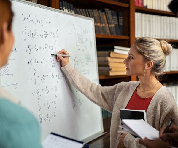 woman with peers doing math on whiteboard